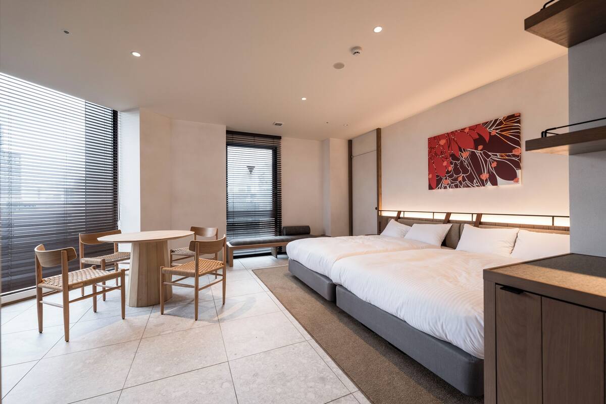 Quarto de hotel moderno com uma cama grande, uma escrivaninha e cadeiras.