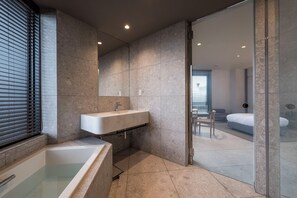 A modern bathroom with a freestanding bathtub, a large mirror, and a glass shower enclosure. - CINQS Hotel (Osaka)