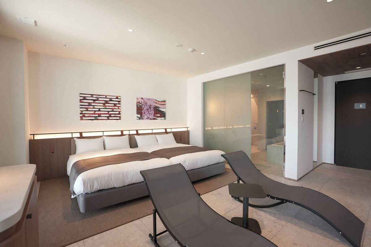 Quarto de hotel moderno com uma cama grande, uma escrivaninha e um painel de vidro.