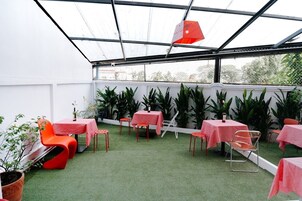 Un jardín interior con mesas y sillas, rodeado de plantas en macetas.