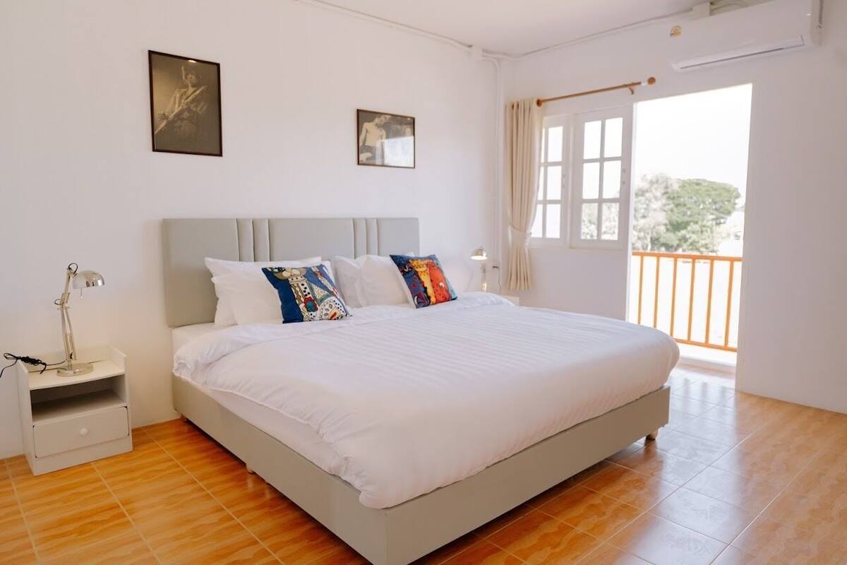 Un dormitorio con cama, mesita de noche y ventana con cortinas.