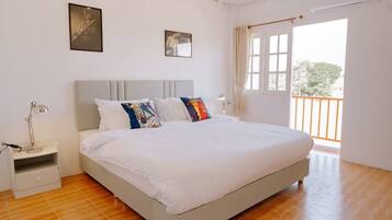 Un dormitorio con cama, mesita de noche y ventana con cortinas.