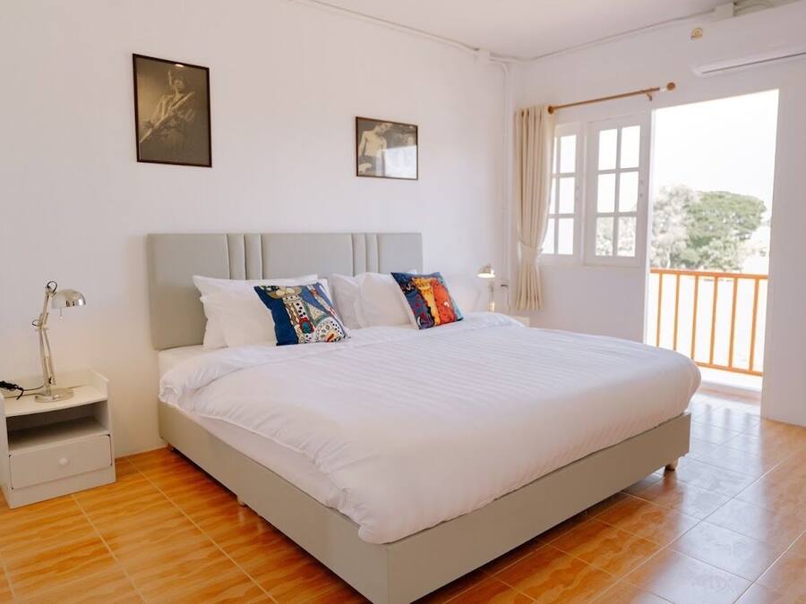 Un dormitorio con cama, mesita de noche y ventana con cortinas.