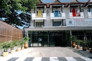 Un edificio con letrero de lavandería, grandes ventanales y plantas en macetas en la entrada.