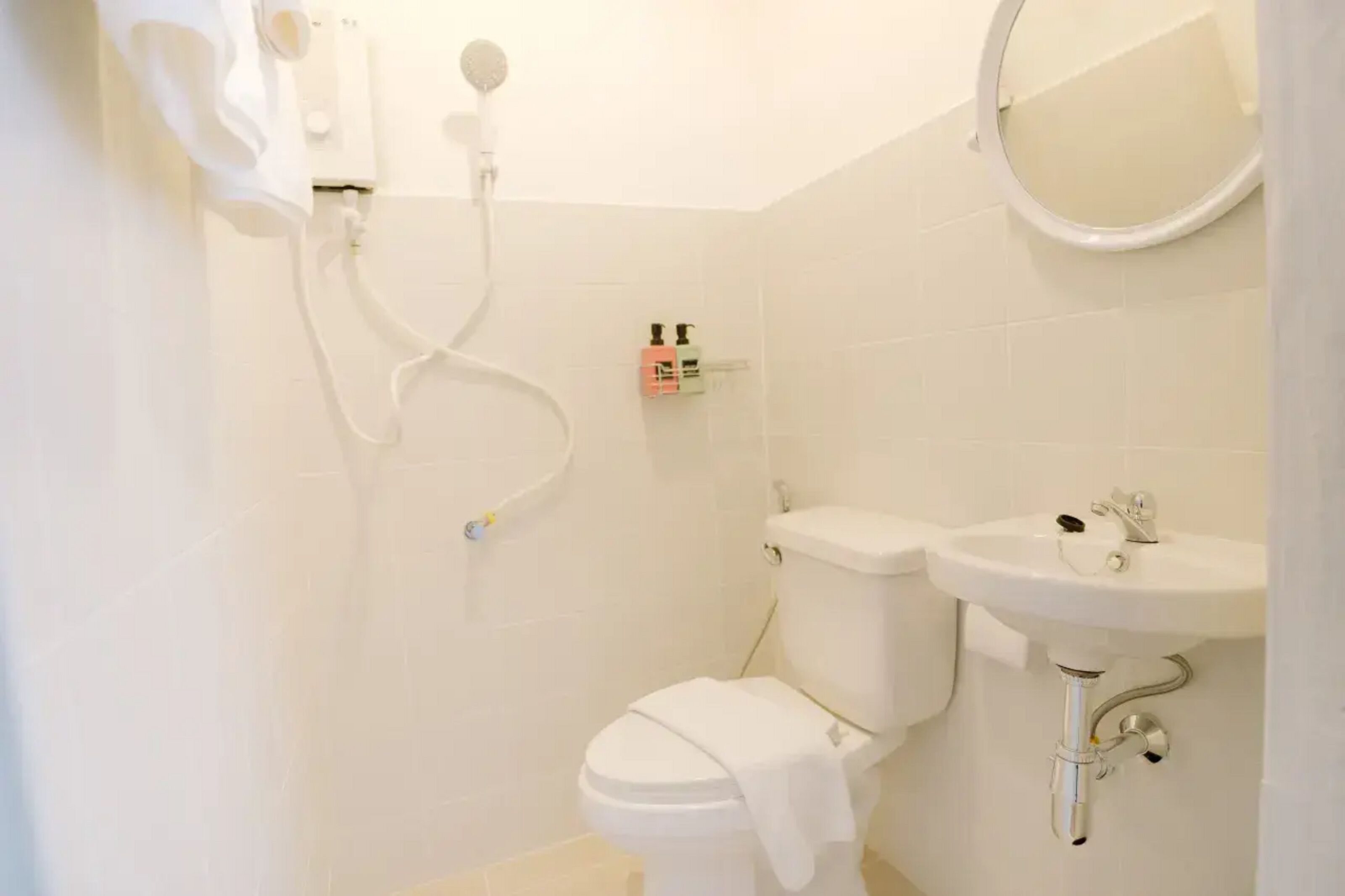 Casa de banho pequena e limpa, com sanita, lavatório e chuveiro.