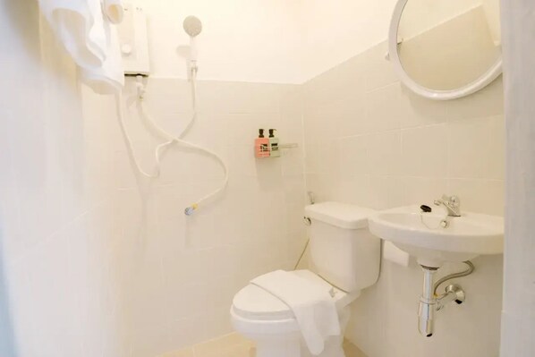 A small, clean bathroom with a toilet, sink, and shower.