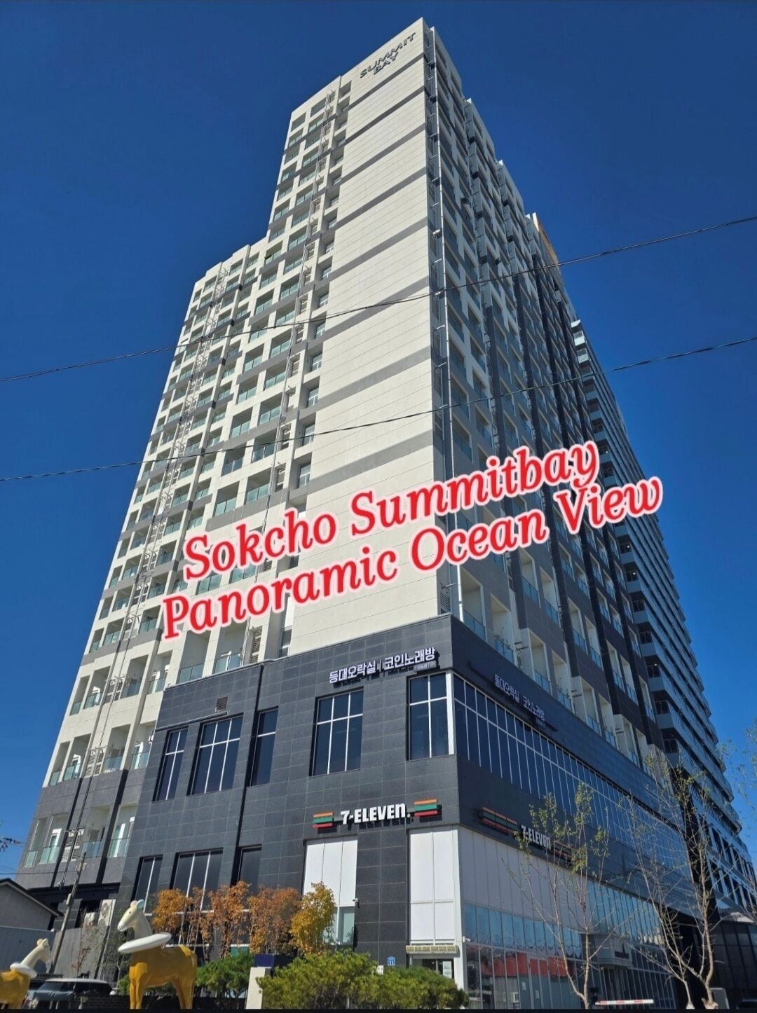 A tall building with multiple floors, a 7-Eleven store on the ground level, and a sign indicating a panoramic ocean view.