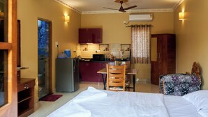 Une chambre d’hôtel de taille réduite, comprenant un lit, un bureau, une chaise et une kitchenette.