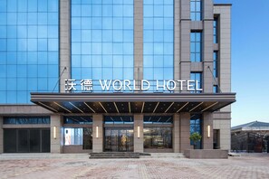 A modern hotel with a large glass facade and a prominent entrance. - World Hotel Hualian Shoppin Plaza branch (Kaifeng)