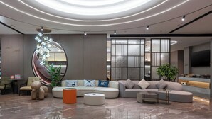 A modern living room with a sectional sofa, a coffee table, and a decorative plant. - World Hotel Hualian Shoppin Plaza branch (Kaifeng)