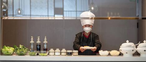 Un chef dans une cuisine professionnelle, avec divers aliments et condiments disposés sur le plan de travail.