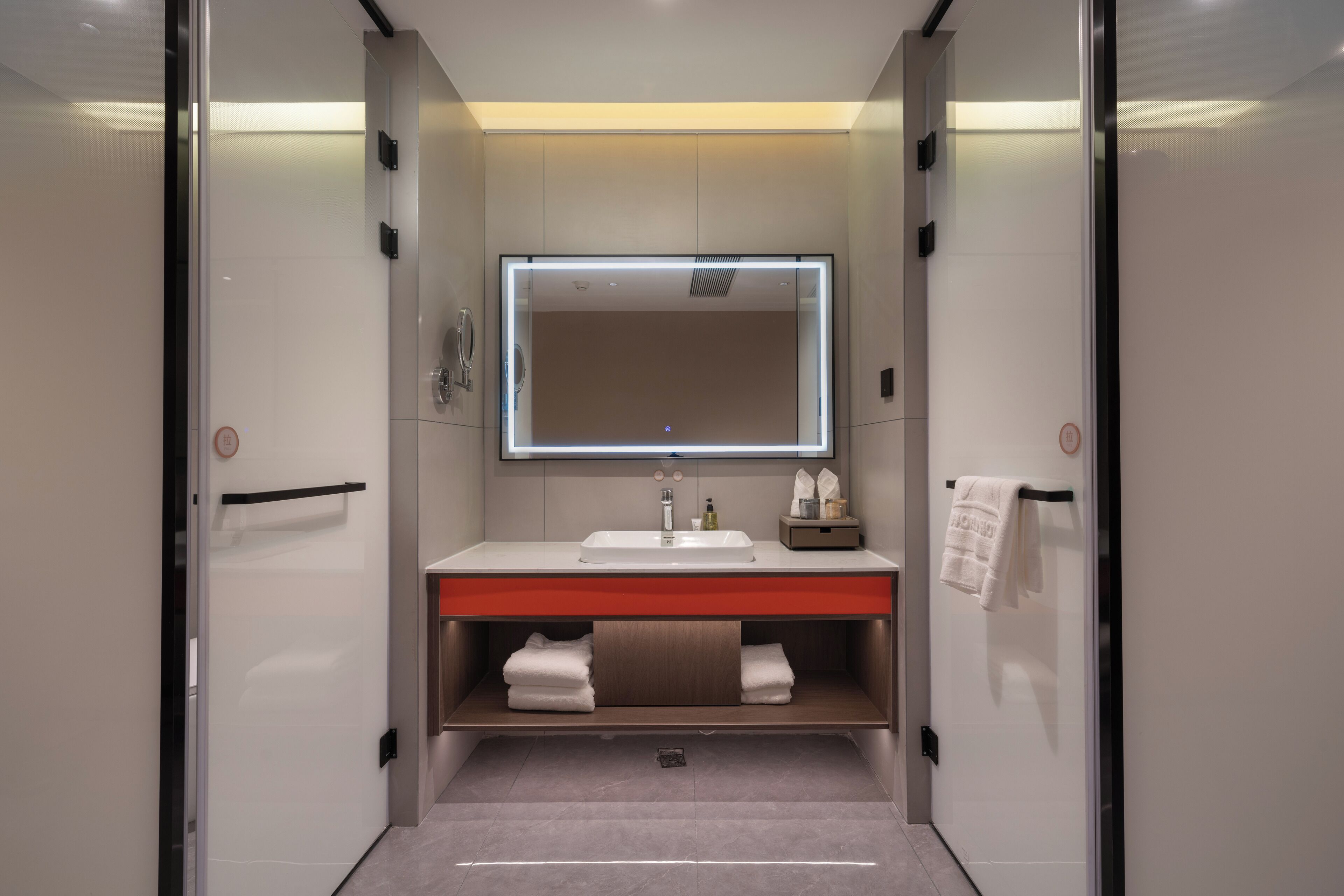 A modern bathroom with a white sink, a mirror, and a towel rack.