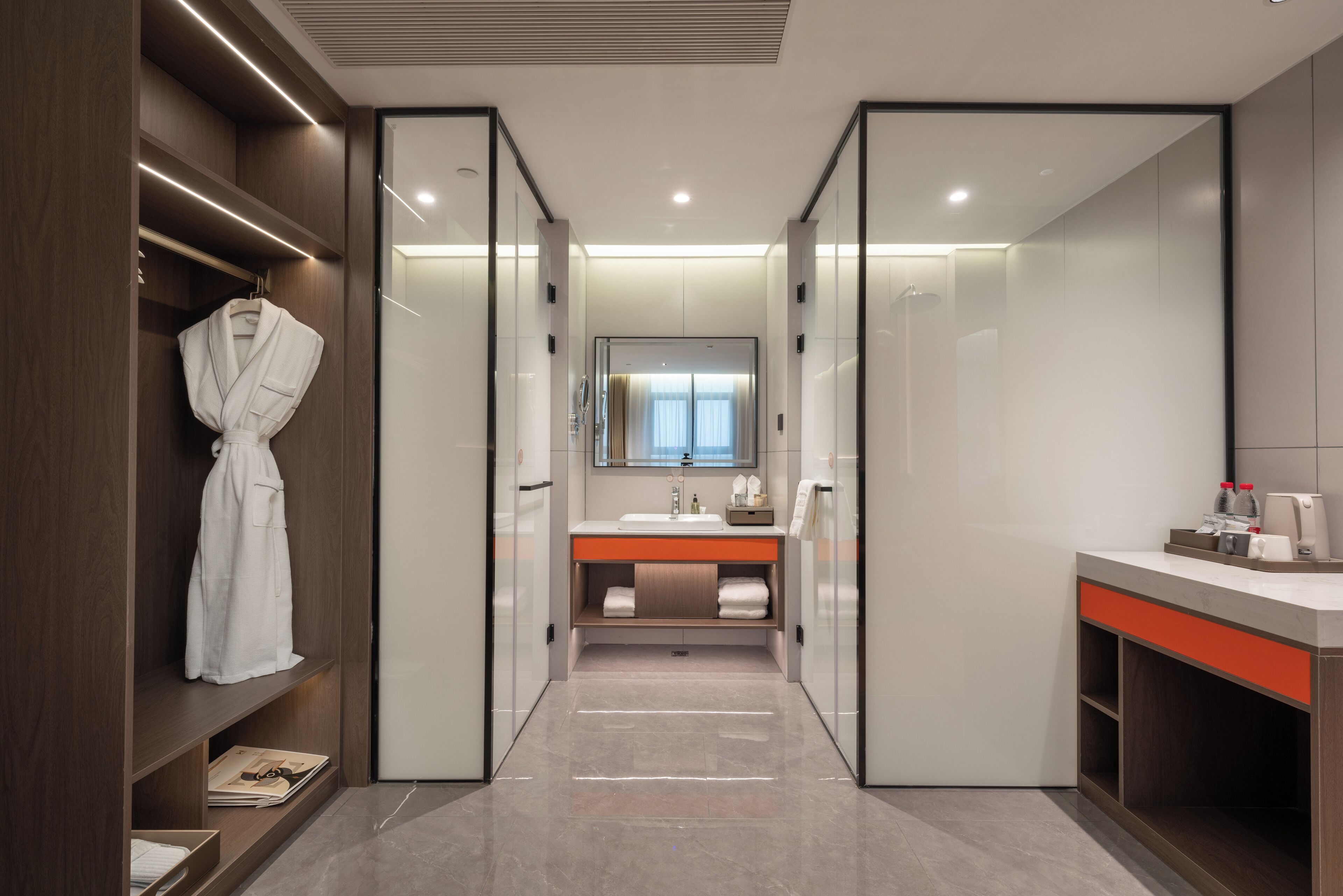 Un baño moderno con cabina de ducha, tocador con espejo y una bata colgada en un estante.