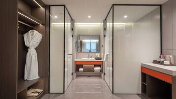 Un baño moderno con cabina de ducha, tocador con espejo y una bata colgada en un estante.