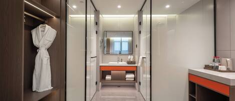 A modern bathroom with a walk-in shower, a vanity with a mirror, and a robe hanging on a shelf.