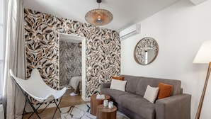 Ein modernes Wohnzimmer mit einem grauen Sofa, einem weißen Sessel und Wandpapier mit Muster.