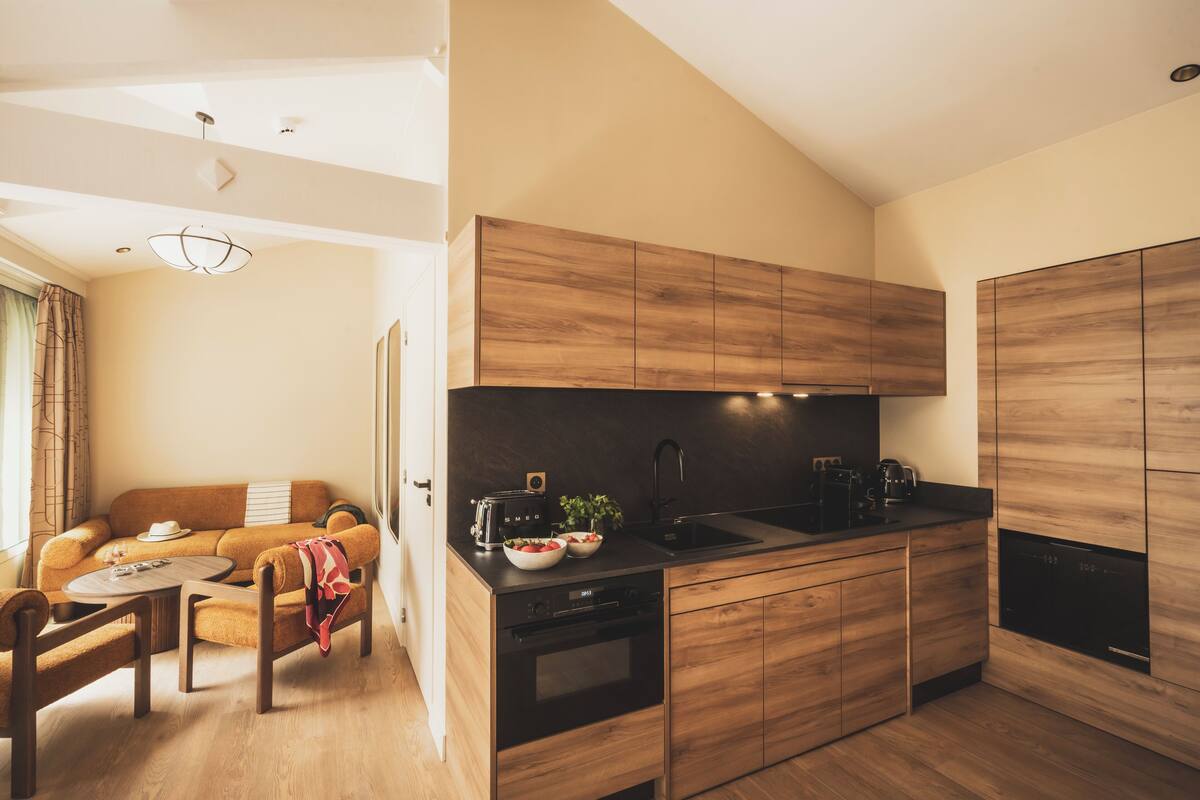 A modern kitchen with wooden cabinets, a black countertop, and a built-in oven.