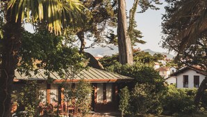 A house with a covered porch, surrounded by lush greenery and a clear view of the mountains in the background. - Parc Victoria Appartements (Saint-Jean-de-Luz)