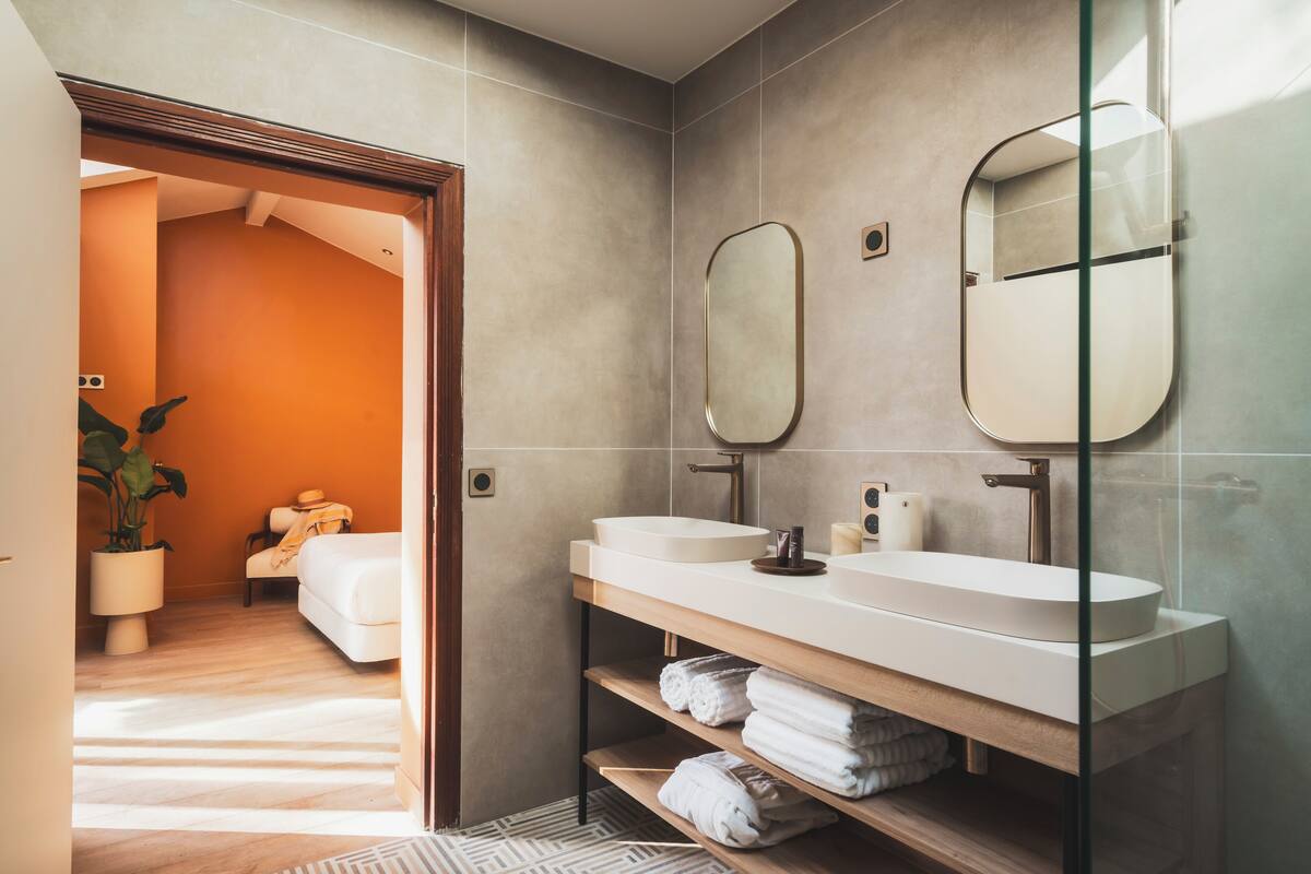 A modern bathroom with two sinks, a large mirror, and a shower.