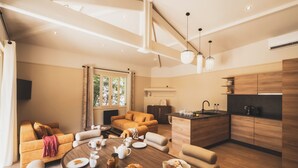 A modern living room with a round dining table, sofa, and kitchen area with wooden cabinets and a sink. - Parc Victoria Appartements (Saint-Jean-de-Luz)