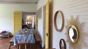 Un comedor con una mesa preparada para cuatro, bancos de madera y una puerta amarilla.