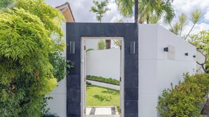Ein moderner Eingangsbereich mit schwarzem Rahmen und weißer Wand, der zu einer gepflegten Gartenanlage führt.