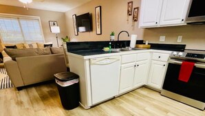 A compact kitchen with white cabinets, a black countertop, and a stainless steel oven. - Eastgate 13A Cozy family retreat close to downtown Hammond (Hammond)