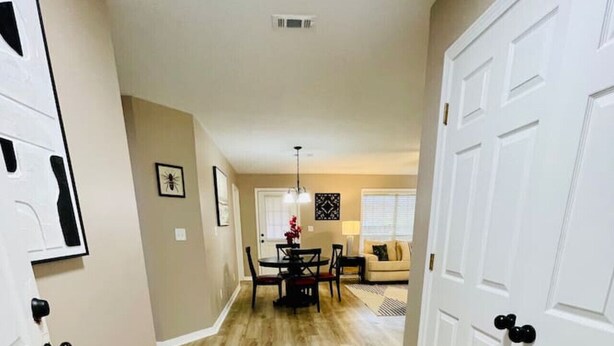 A hallway with wooden flooring, white doors, and a dining area with a table and chairs. - Eastgate 13A Cozy family retreat close to downtown Hammond (Hammond)