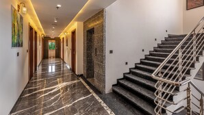 Ein Korridor mit Marmorboden, einer Treppe mit Metallgeländern und einer Tür am Ende.