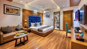 Ein modernes Hotelzimmer mit einem großen Bett, einer Couch, einem Couchtisch und einem Fernseher.