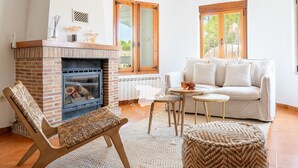 A cozy living room with a brick fireplace, a sofa, a chair, and a small table. - CostaBlancaDreams - Casa Charline in Calpe (Calpe)