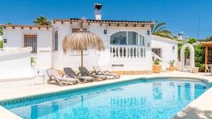 A swimming pool with lounge chairs, a thatched umbrella, and a white building with a tiled roof. - CostaBlancaDreams - Casa Charline in Calpe (Calpe)