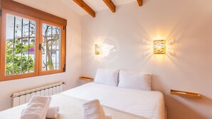 A bedroom with a large bed, wooden beams, a window with a view, and wall-mounted lights. - CostaBlancaDreams - Casa Charline in Calpe (Calpe)