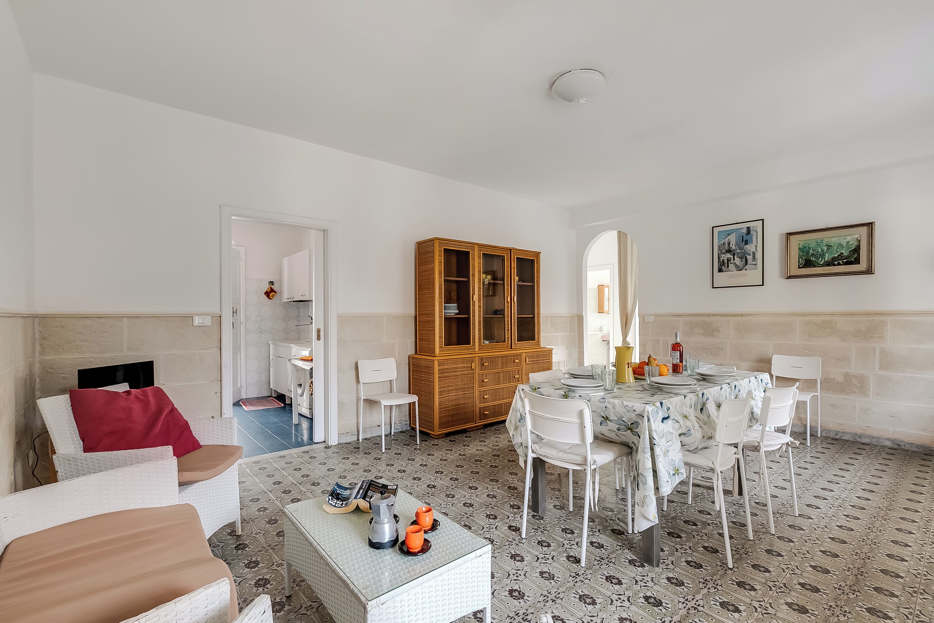Un coin repas avec une table ronde, des chaises blanches et un buffet.