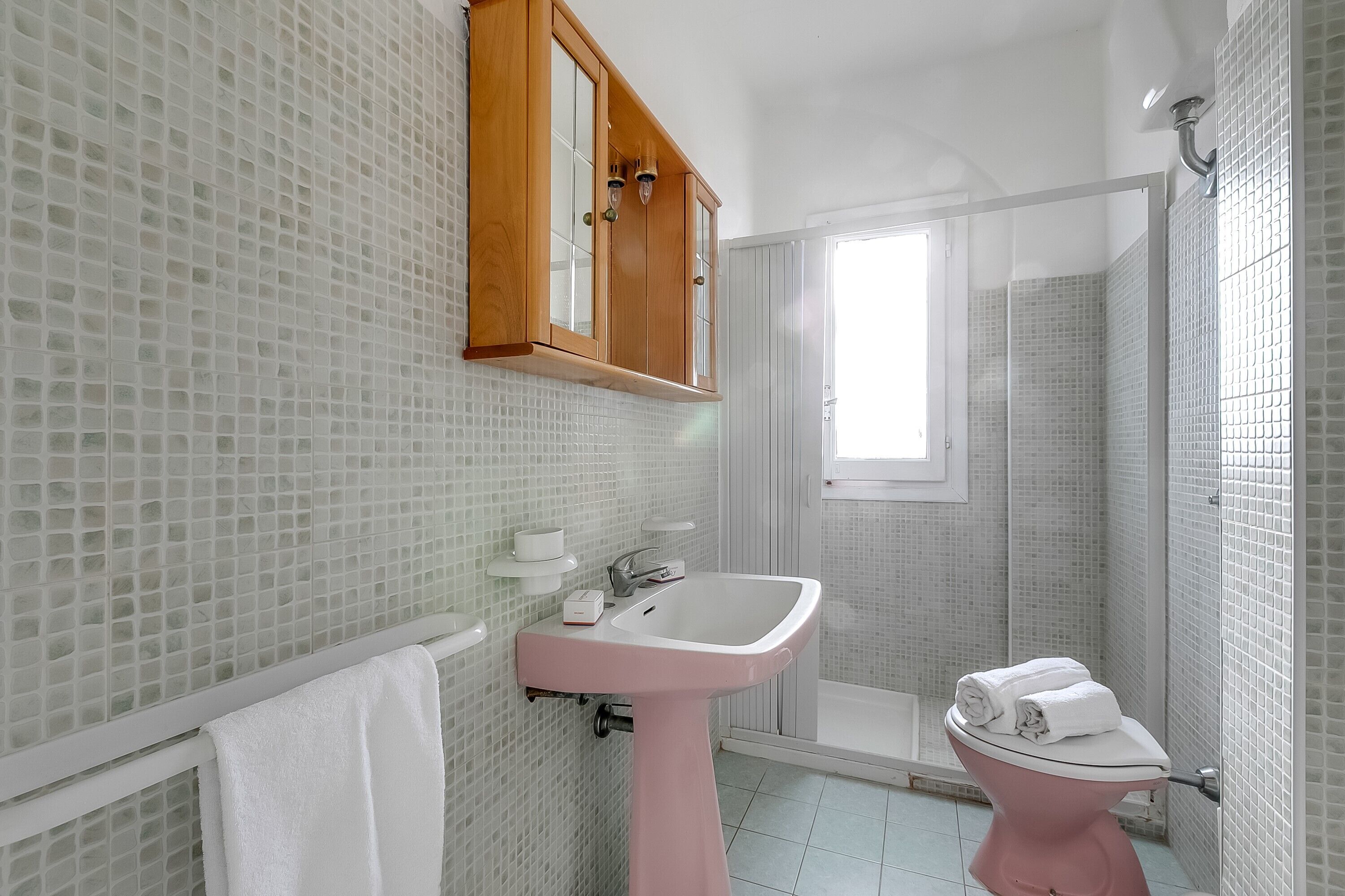 A bathroom with a pink sink, a toilet, and a shower.