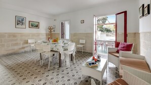 Un coin repas avec une table ronde, des chaises et une table basse sur laquelle sont posés des livres et des tasses.