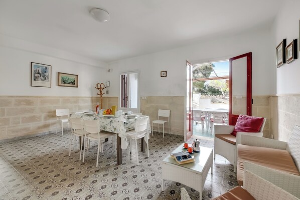 A dining area with a round table, chairs, and a coffee table with books and cups.