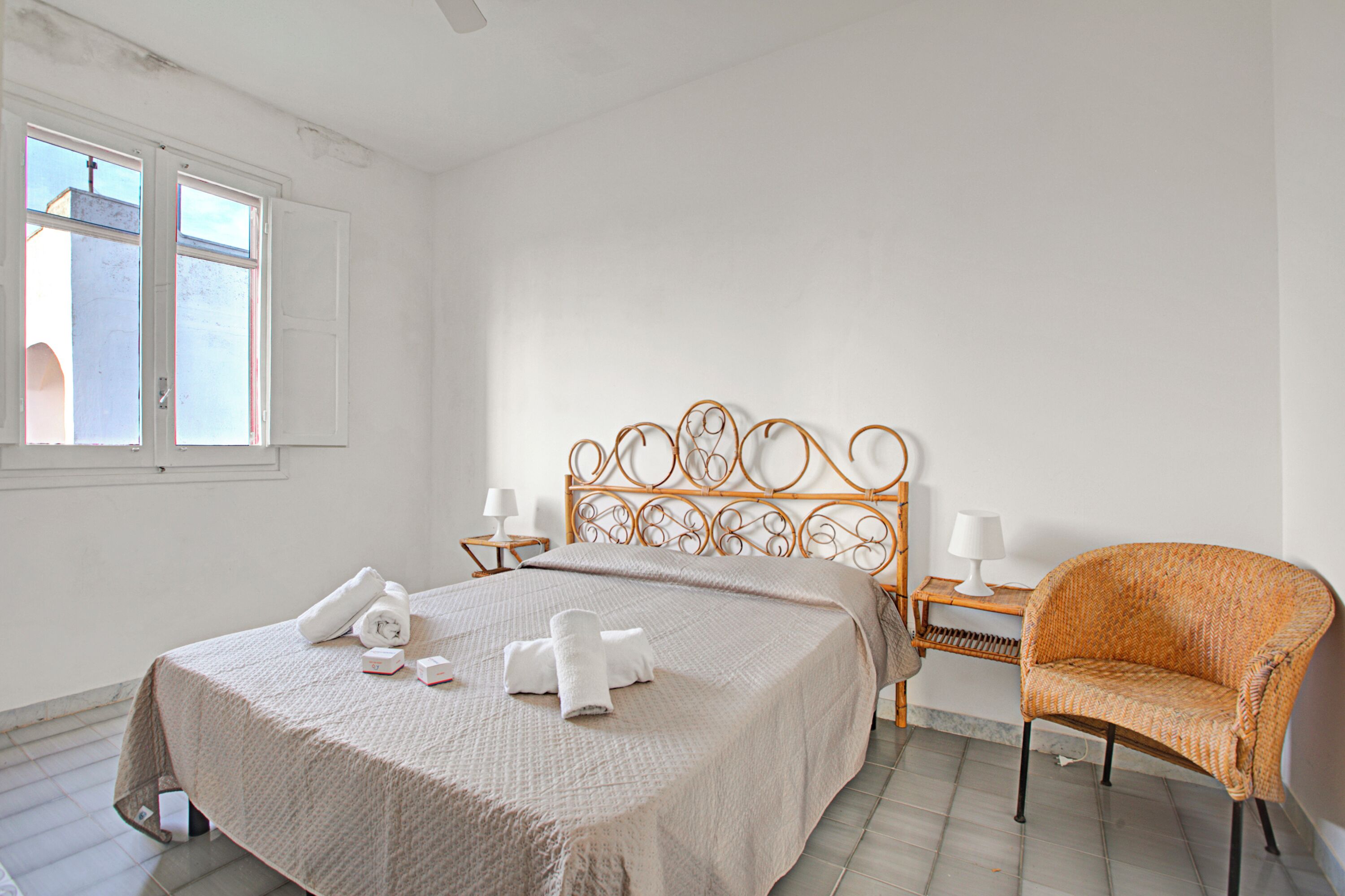 Een slaapkamer met een bed, een stoel, een nachtkastje en een raam.
