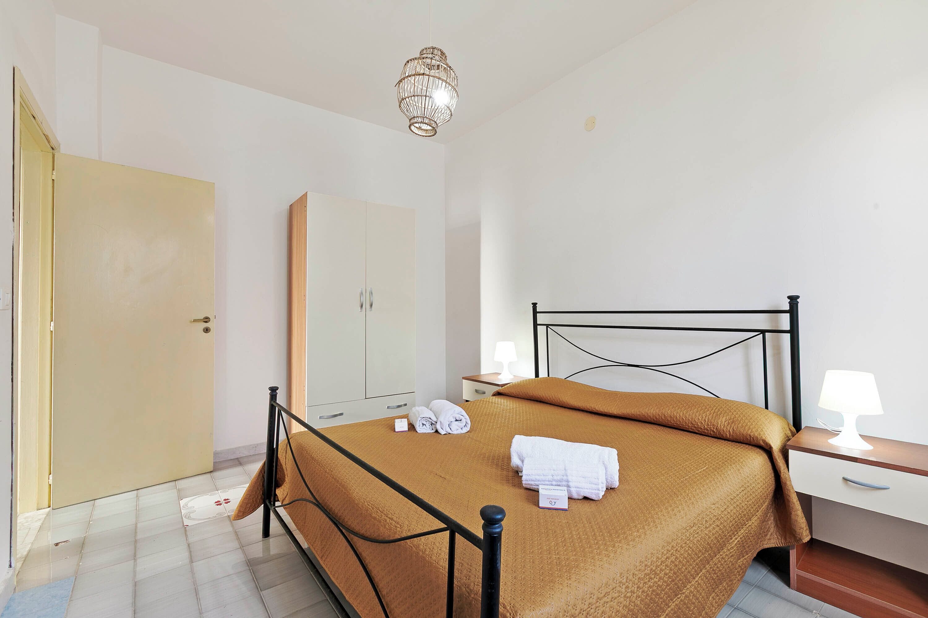 Ein Hotelzimmer mit Bett, Schrank, Nachttisch mit Lampe und Tür.