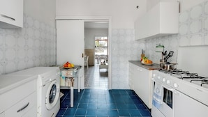 Une cuisine compacte équipée d’un lave-linge, d’une cuisinière et d’un coin repas visible à travers une porte ouverte.