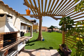 A patio area with a grill, outdoor seating, and a pergola structure.
