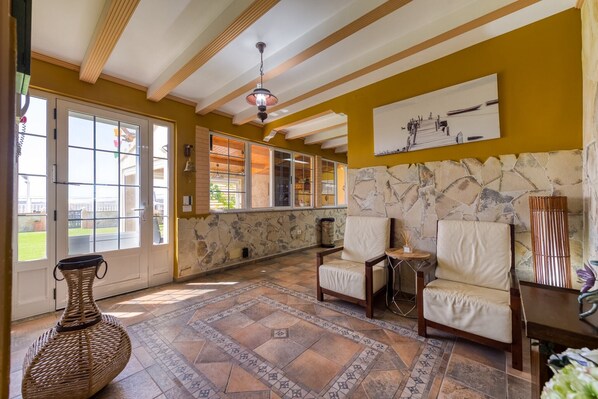 Una habitación amplia con ventanas grandes, una pared de acento de piedra y un ventilador de techo.