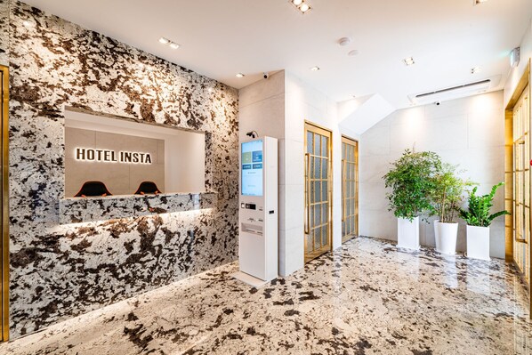 A hotel reception area with a marble wall, a digital screen, and a reception desk. - Insta Hotel - Main Branch (Suwon)