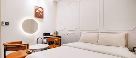 Une chambre d’hôtel comprenant un lit, deux chaises, une petite table, un miroir et une œuvre d’art accrochée au mur.