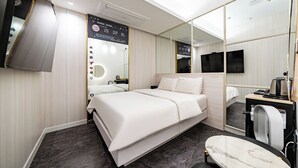 A modern hotel room with a bed, a small table, a mirror, a TV, and a wall-mounted control panel. - Insta Hotel - Main Branch (Suwon)