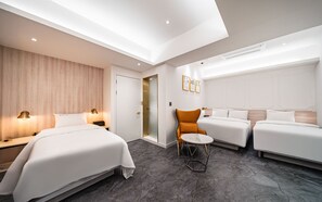 Una habitación de hotel moderna con dos camas, una mesita redonda pequeña y una silla.