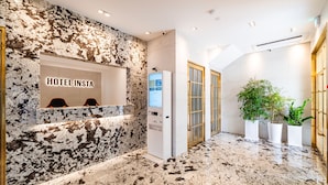 A hotel reception area with a marble wall, a digital screen, and a reception desk. - Insta Hotel - Main Branch (Suwon)