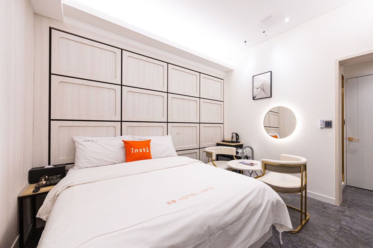 Una habitación de hotel con cama, mesita de noche y un espejo redondo.