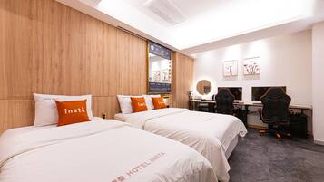 A hotel room with two beds, a desk, a chair, and a mirror.
