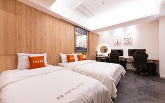 Habitación de hotel con dos camas, un escritorio, una silla y un espejo.